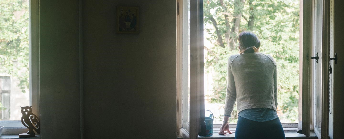 En kvinna tittar ut genom ett fönster