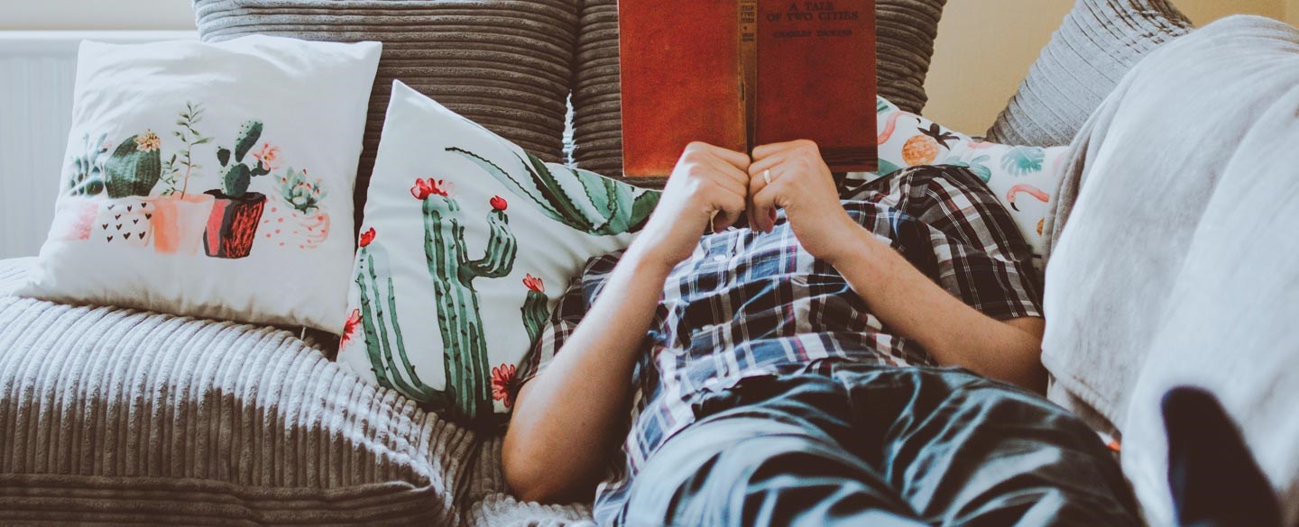 En person läser en bok i soffan