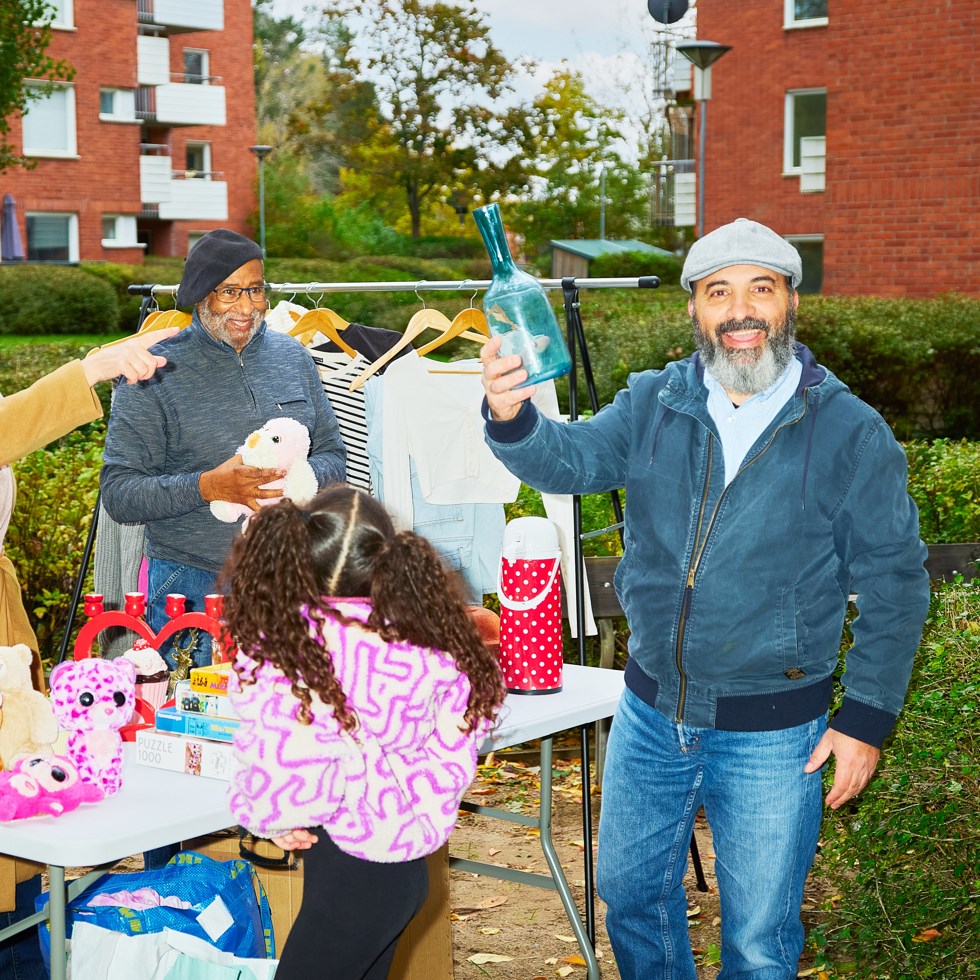 en man håller upp fynd på loppmarknad, en flaska.