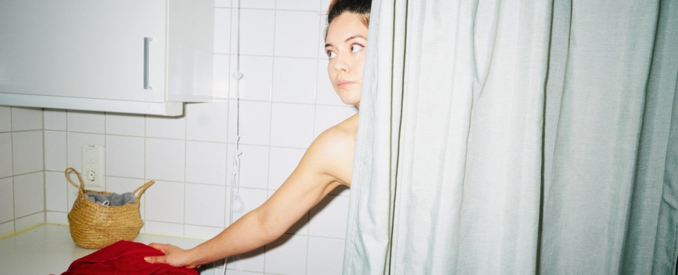 Allvarlig kvinna tittar ut från duschen