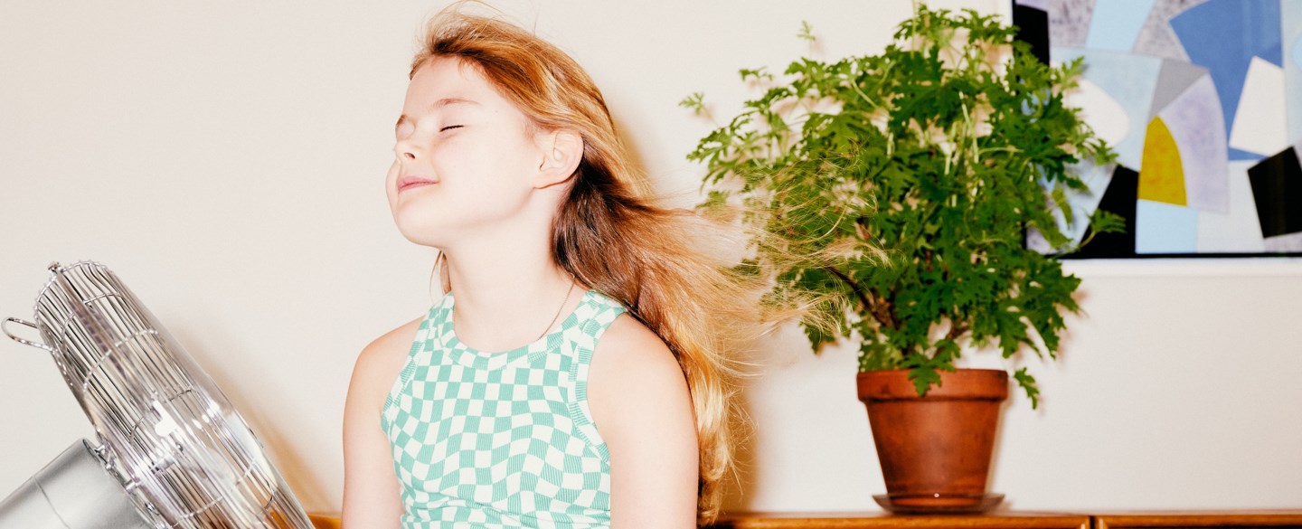 En flicka sitter framför en fläkt.