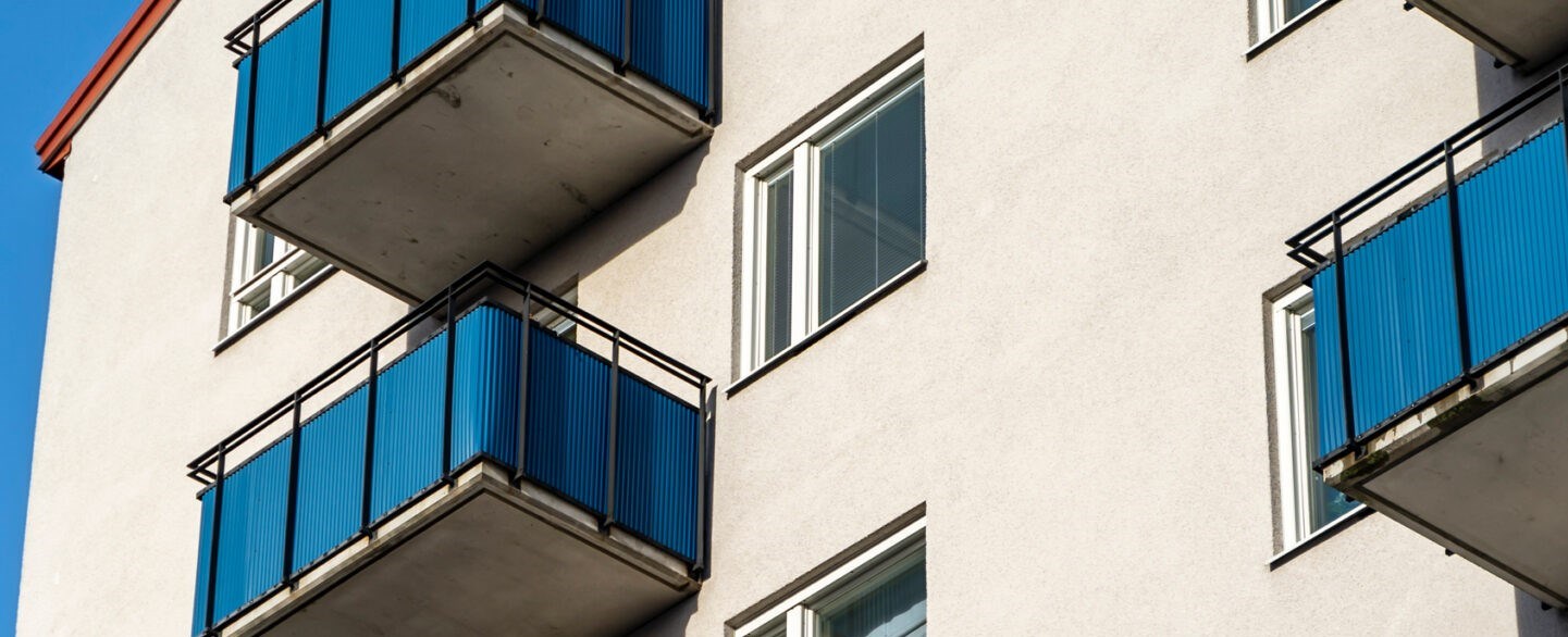 Gulbeige husfasad med fönster och blå balkonger