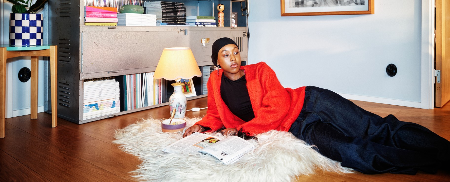 kvinna röd tröja ligger och läser på en vit ryamatta