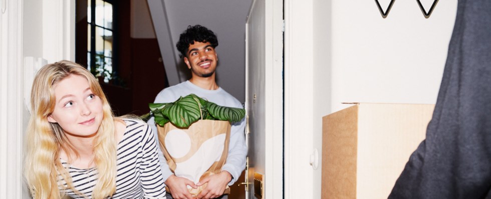 Tre personer flyttar. De bär på flyttkartonger.