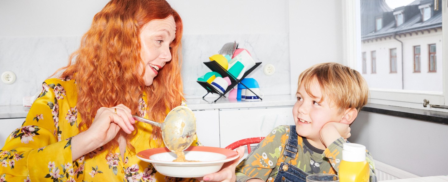 En mamma och son äter mat i köket.