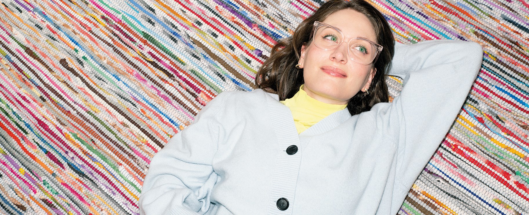 Ung kvinna ligger på matta och funderar och ser rofylld ut