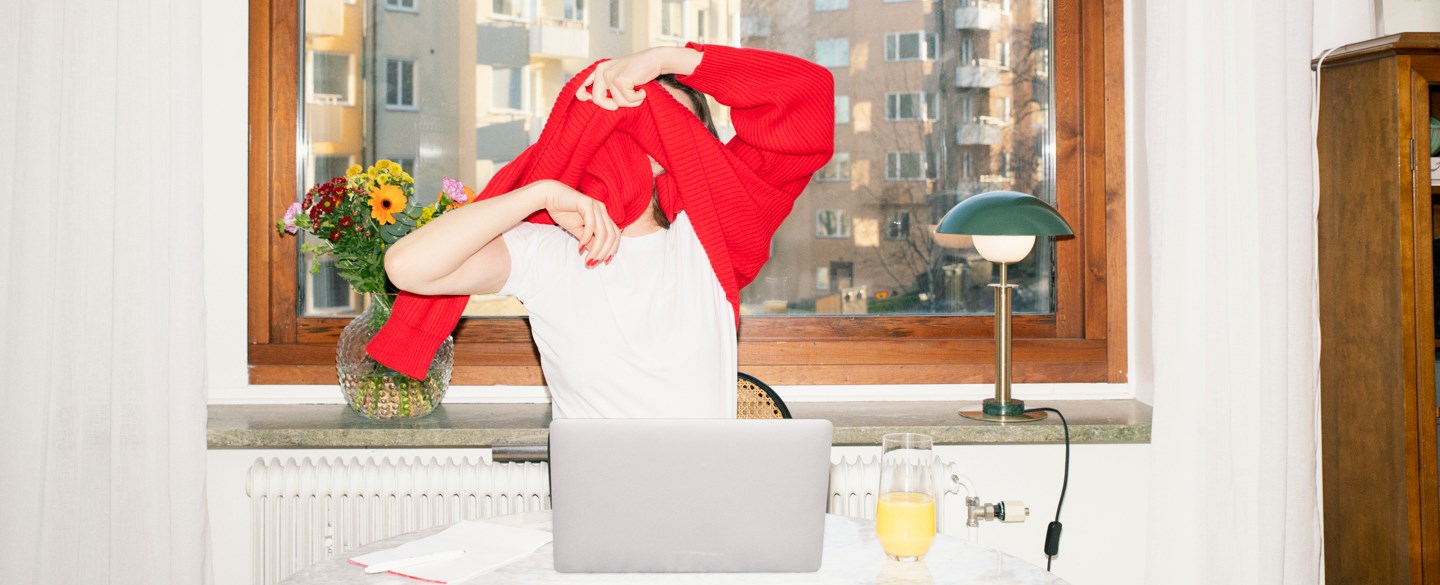 En kvinna tar av sig sin röda tröja.