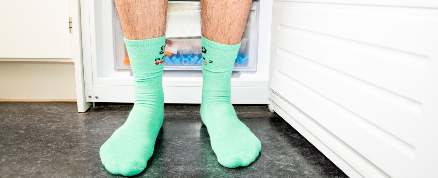 Två par fötter iklädda gröna strumpor står framför en öppen frys