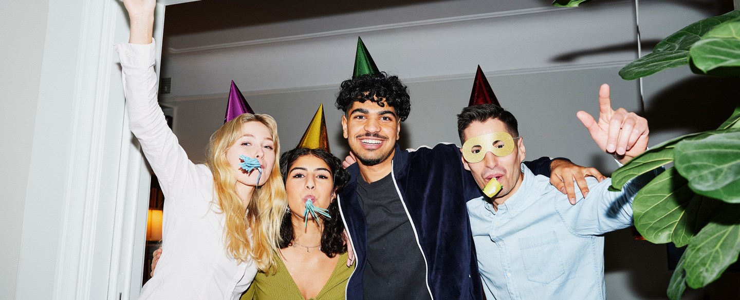 Fyra personer står och ler i en dörröppning på en fest.