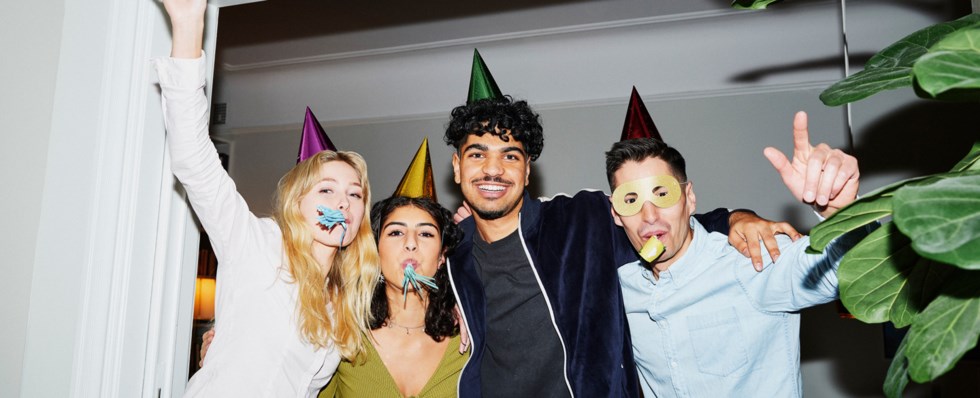 Fyra personer står och ler i en dörröppning på en fest.