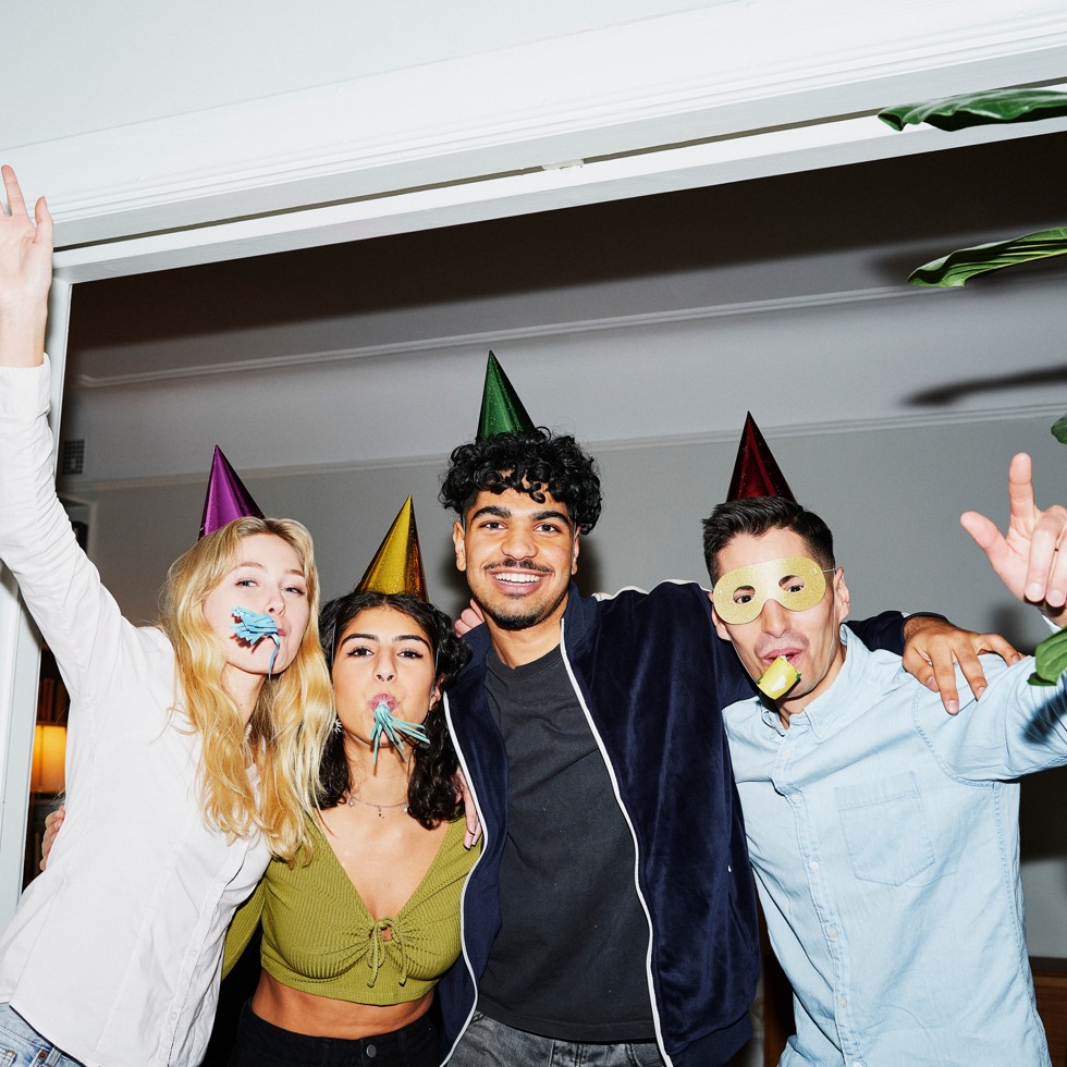 Fyra personer står och ler i en dörröppning på en fest.