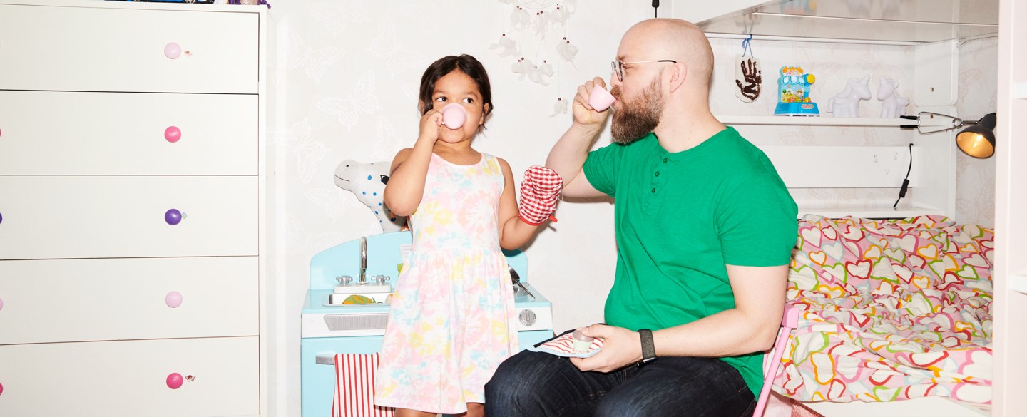 En pappa och ett barn dricker te i ett barnrum.