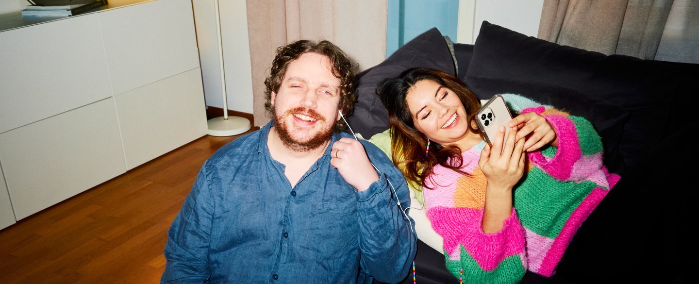 par myser vid soffan och lyssnar på mobil