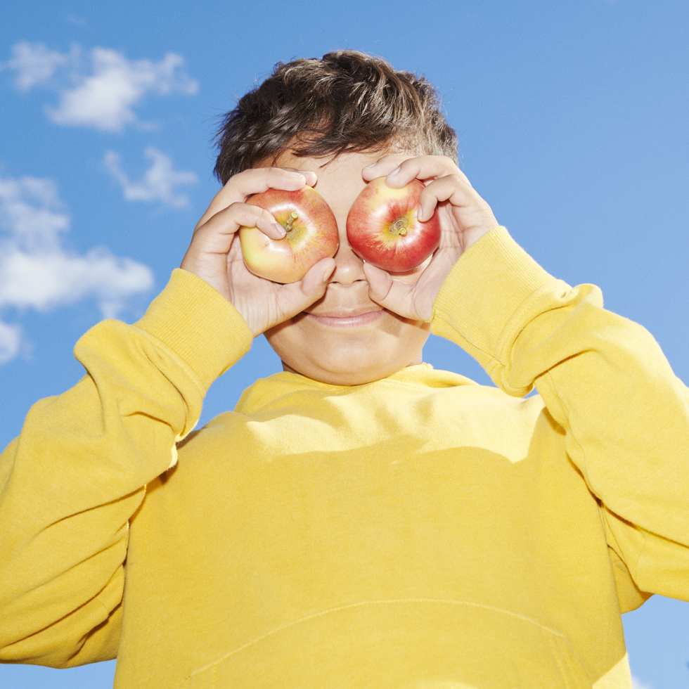 pojke håller äpplen för ögonen