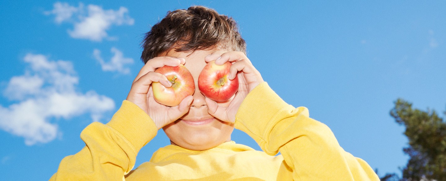 pojke håller äpplen för ögonen