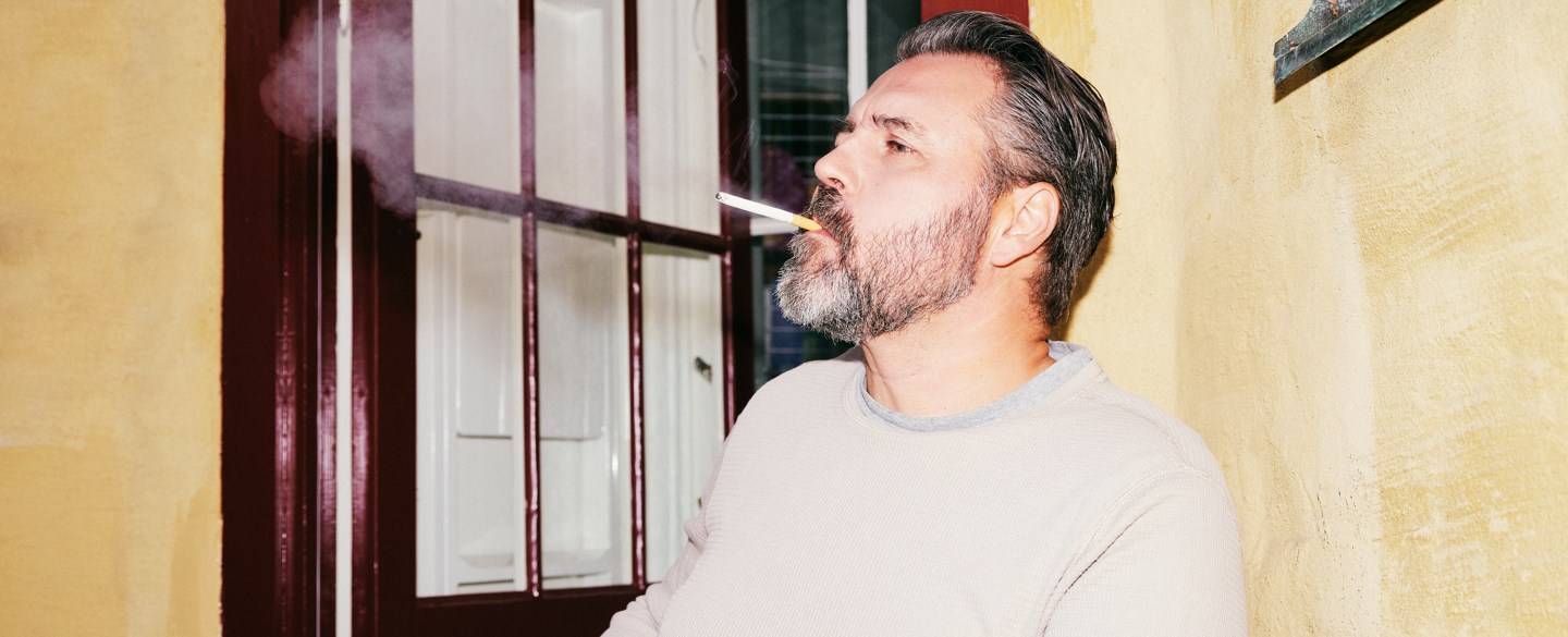 En man röker en cigarett på balkongen.