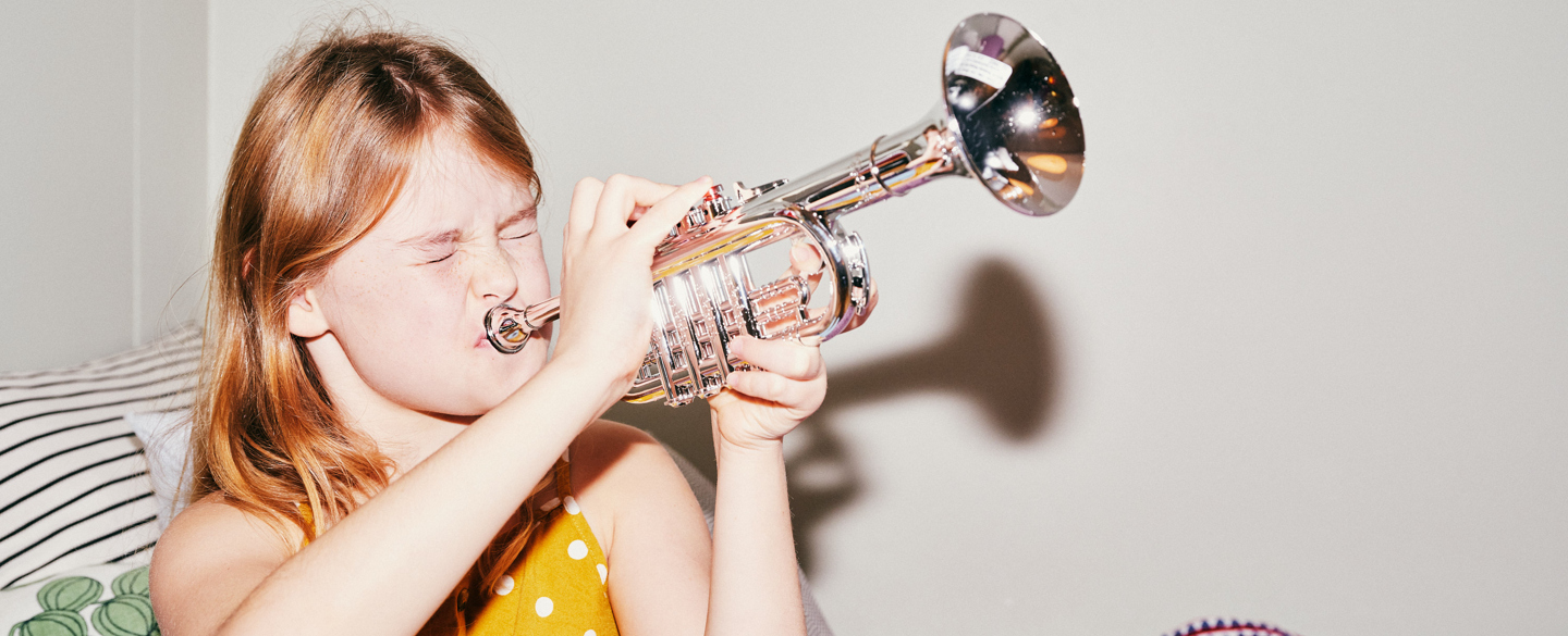 En flicka blåser i en trumpet.