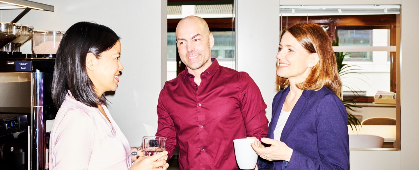 kollegor strå med kaffekopp på kontor och pratar