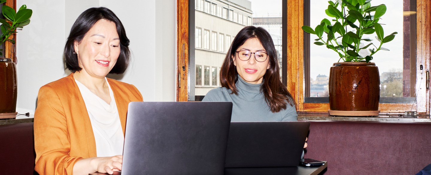 två kvinnor sitter brdvid varandra ocg arbetar vid dator