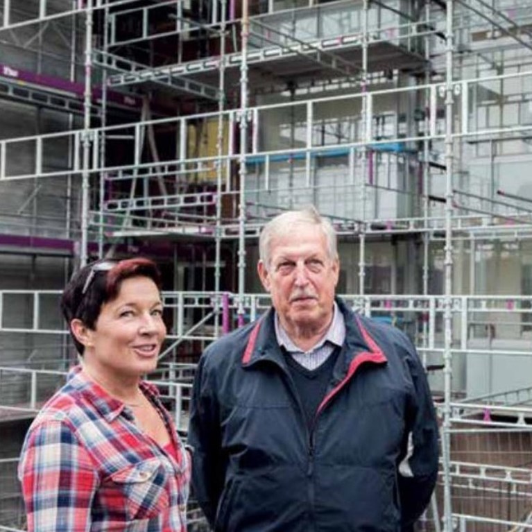 Bilden visar en man och en kvinna vid en byggnadsställning