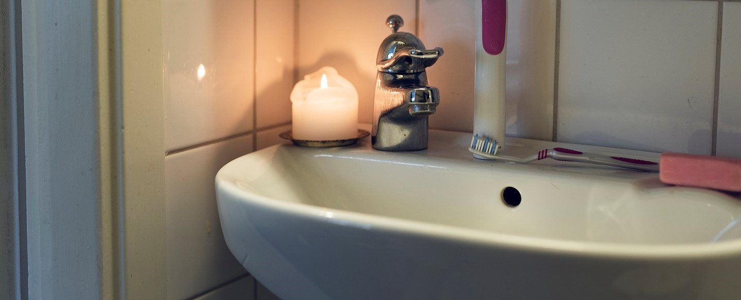 Tandborstar och ett tänt ljus som står på ett handfat