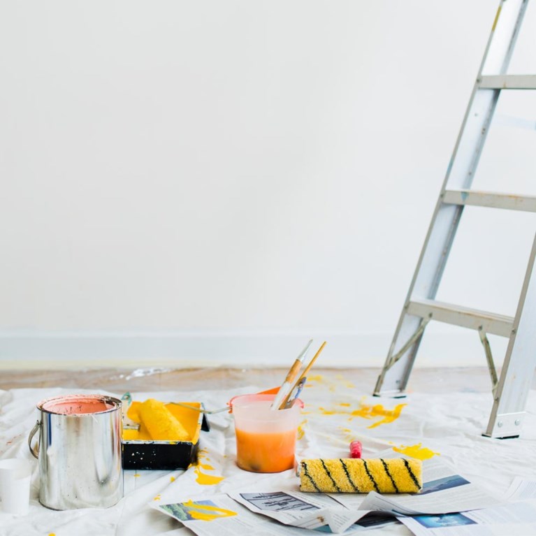 På bilden finns målarburkar och en stege i ett rum